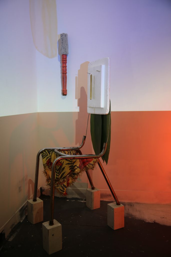 Lola Queen Supreme (installation view, SVA MFA Open Studios), 2017 chair frame, fabric, tinsel, plastic ti leaves, styrofoam, comb, wire, wood blocks approx. 46” x 14” x 21”